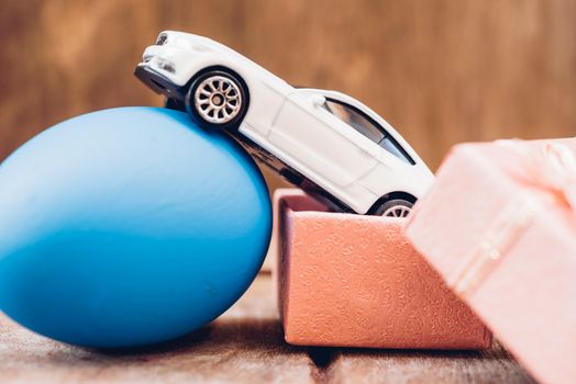 Easter egg and toy car on wooden background, happy easter day concept