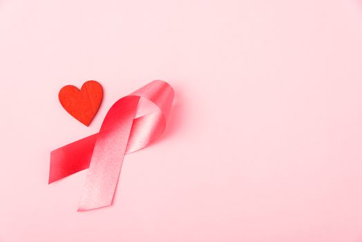 Breast cancer month health concept, flat lay top view, put pink ribbon and Red Heart on pink background with copy space for your text