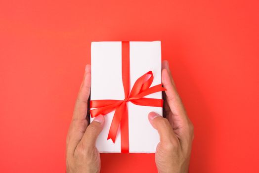 Valentine's Day Concept, Top view Flat lay, Hand holding gift box on red background with copy space for your text