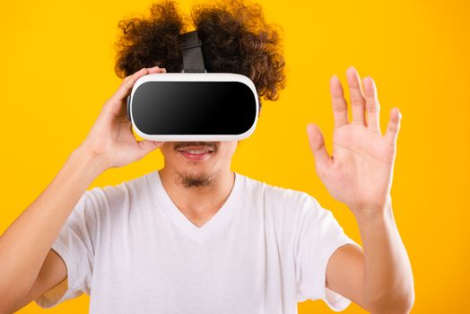 Asian handsome man with curly hair he using virtual reality headset or VR glass isolate on yellow background