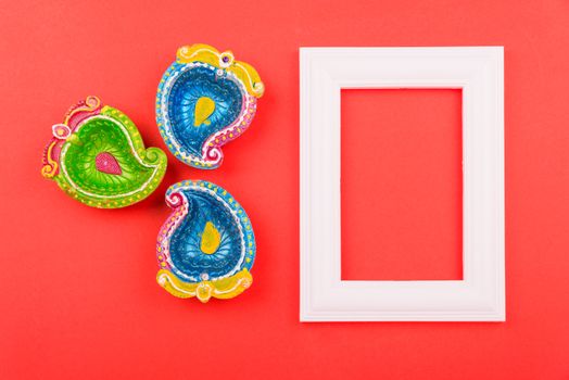 Happy Diwali Day, Flat lay top view Colorful Clay Diya lamps and photo frame on red background and copy space for your text
