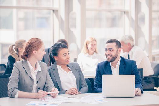 Business team sitting by the table with laptop and documents in office