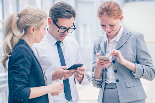 Business people with mobile phones surfing the net at break in office