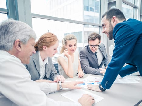 Group of business people discussing diagrams in office together