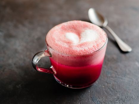Trendy drink: pink red velvet latte. Beetroot cappuccino or latte in glass cup on black background. Copy space for text.
