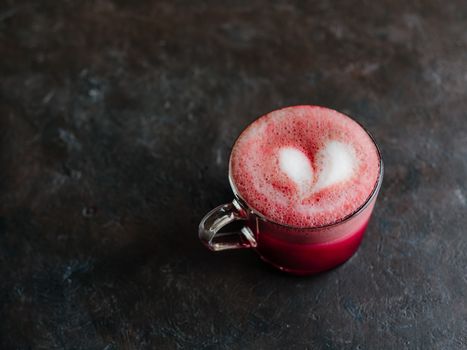Trendy drink: pink red velvet latte. Beetroot cappuccino or latte in glass cup on black background. Copy space for text.
