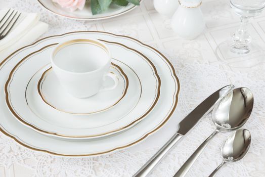 Beautifully decorated table with white plates, crystal glasses, linen napkin, cutlery and rose flowers on luxurious tablecloths