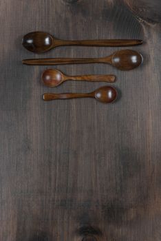 Wooden spoons lie on a dark wooden background with copy-space