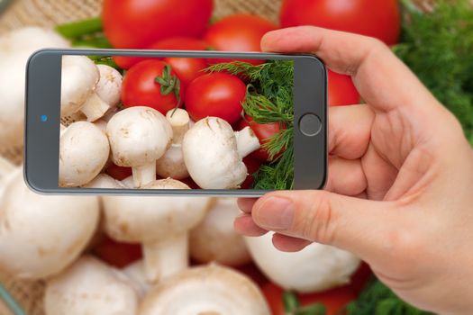 Fresh vegetables. Ingredients for cooking. Tomatoes and champignons on the smartphone screen.