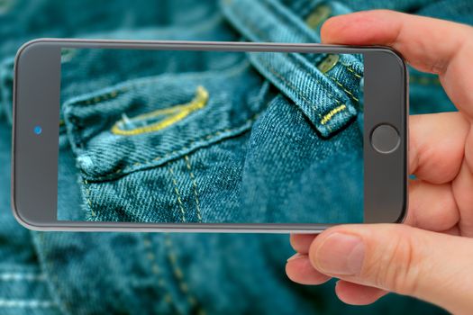 Blue jeans stitched with yellow thread. Blue jeans on smartphone screen.