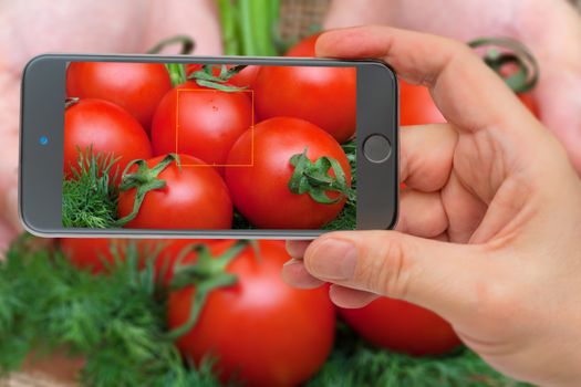 Ingredients for cooking. Tomatoes in the smartphone screen.