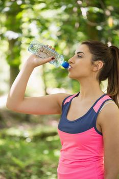 Handsome brunette woman drinking water outdoors in a forest
