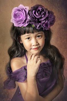 Cute asian little girl with wreath of flowers on her head