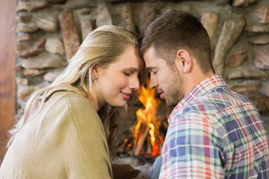 Side view of a romantic young couple with eyes closed in front of lit fireplace