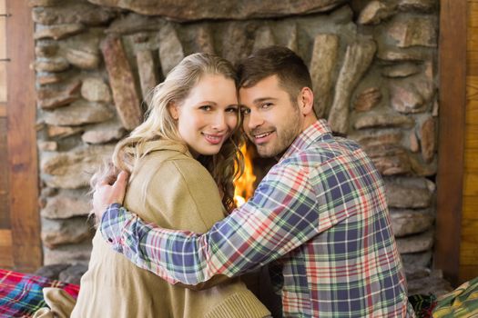 Rear view portrait of a romantic young couple in front of lit fireplace