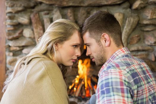 Side view of a romantic young couple in front of lit fireplace