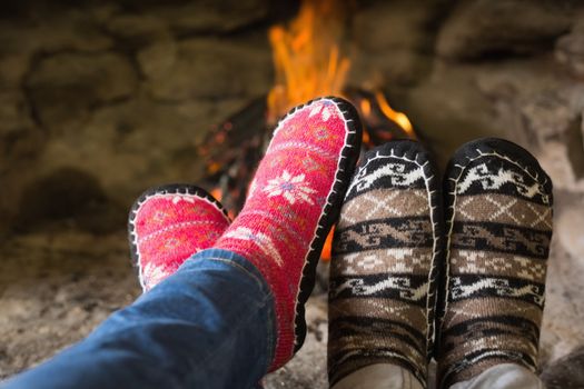 Close up of romantic couples legs in socks in front of fireplace at winter season at home