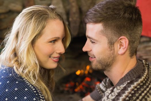 Close up side view of a romantic young couple smiling in front of fireplace