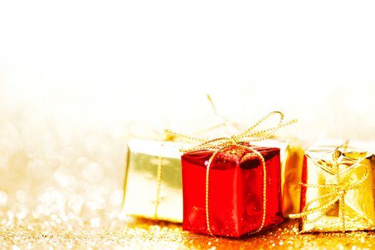 Decorative red and gold boxes with holiday gifts on shiny glitter background
