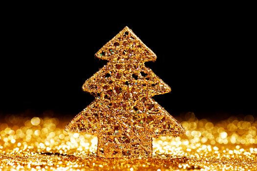 Beautiful golden decorative christmas tree on golden glitter background with black copy space