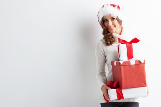 Happy woman in Santa hat with stack of Christmas gifts