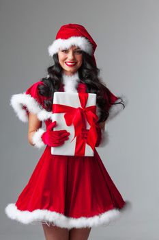 Woman in red Santa Claus outfit holding christmas gift box