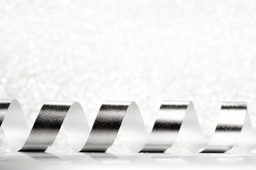 Curly silver serpentine on shiny glitter background, holiday concept