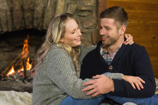 Lovely romantic young couple in front of lit fireplace