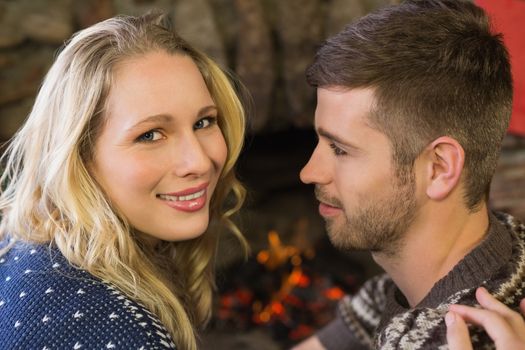 Close up portrait of a romantic young couple smiling in front of fireplace