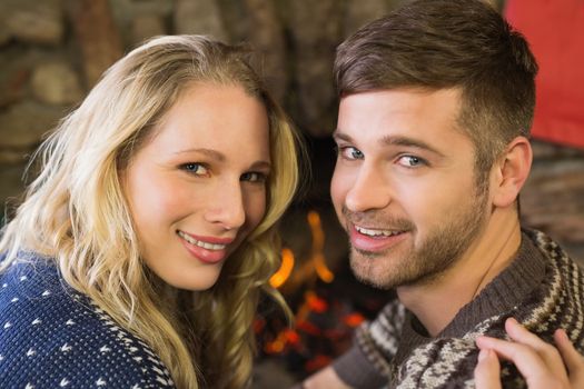 Close up portrait of a romantic young couple smiling in front of fireplace