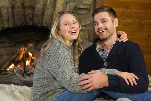 Portrait of a lovely romantic young couple in front of lit fireplace