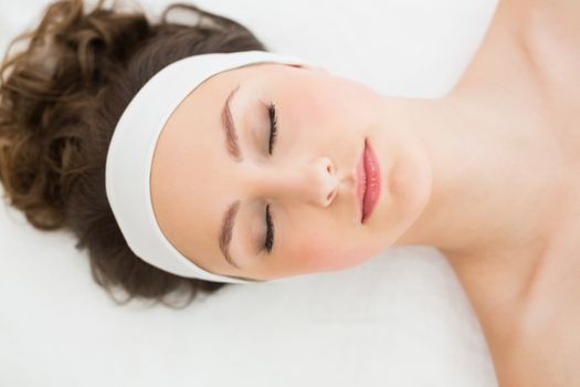Young brunette lying on massage table with eyes closed in beauty salon