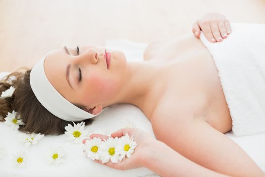 Side view of a young beautiful woman with eyes closed lying on massage table in beauty salon