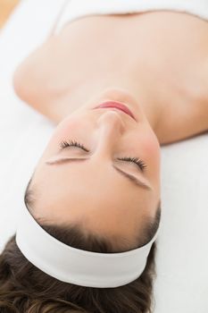 Young brunette lying on massage table with eyes closed in beauty salon