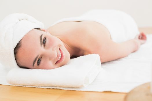 Portrait of a beautiful young woman resting on towel at beauty spa
