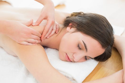 Close up of a beautiful woman enjoying shoulder massage at beauty spa