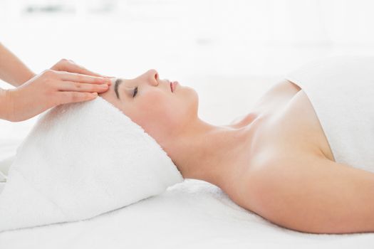 Side view of hands massaging a beautiful womans forehead at beauty spa