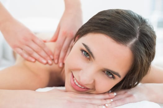 Portrait of a smiling beautiful woman enjoying shoulder massage at beauty spa