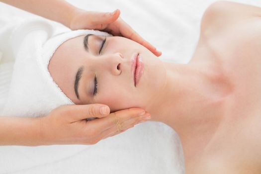 Close up of hands massaging a beautiful womans face at beauty spa