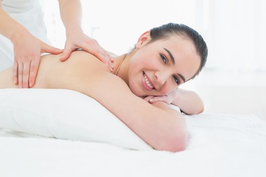 Side view of a beautiful woman enjoying back massage at beauty spa