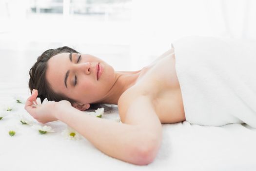 Beautiful young woman with flowers lying in beauty salon