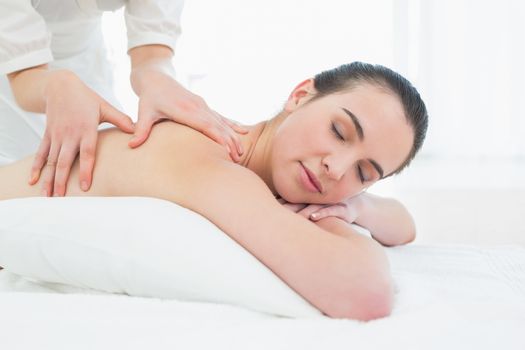 Side view of a beautiful woman enjoying back massage at beauty spa