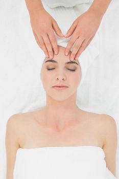 Close up of hands massaging a beautiful womans forehead at beauty spa