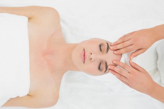 Close up of hands massaging a beautiful womans forehead at beauty spa