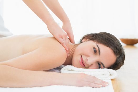 Portrait of a smiling beautiful woman enjoying shoulder massage at beauty spa