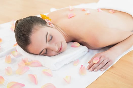Beautiful young woman resting with eyes closed on towel at beauty spa