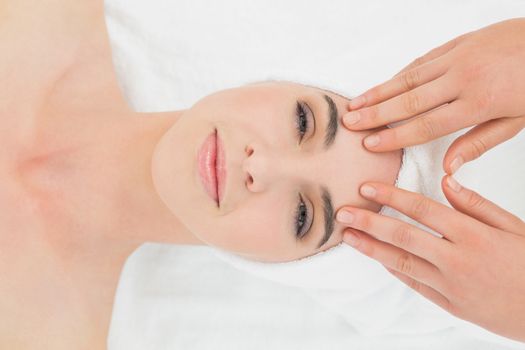 Close up of hands massaging a beautiful womans forehead at beauty spa