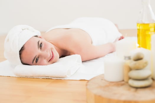 Beautiful young woman resting with oil bottle in foreground at beauty spa