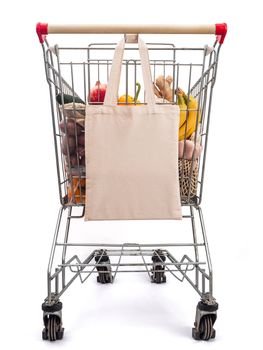 Empty textile eco bag supermarket near shopping trolley cart. Food waste, zero waste shopping concept.