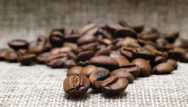 heap of roasted coffee beans on a matting macro beige background closeup